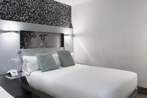 a bedroom with a white bed with green pillows at Petit Palace Plaza Mayor in Madrid