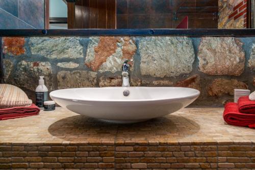 a white sink in a bathroom with a stone wall at Sithonian Blue Royal Villa in Nikiti