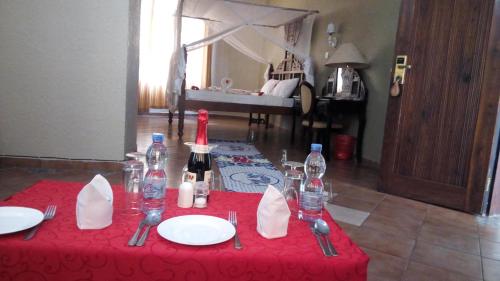 una mesa roja con platos y botellas de vino. en Serene Hotel en Dar es Salaam
