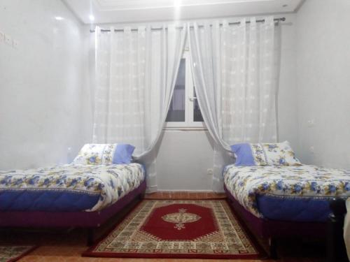 two beds in a room with a window at Marrakech autrement in Marrakesh