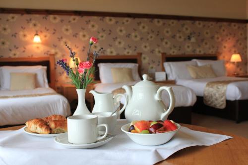 a room with two beds and a table with cups and plates of fruit at Silver Tassie Hotel & Spa in Letterkenny