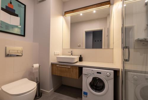 ein Badezimmer mit einer Waschmaschine und einem Waschbecken in der Unterkunft City Lights Rakowicka 15 in Krakau
