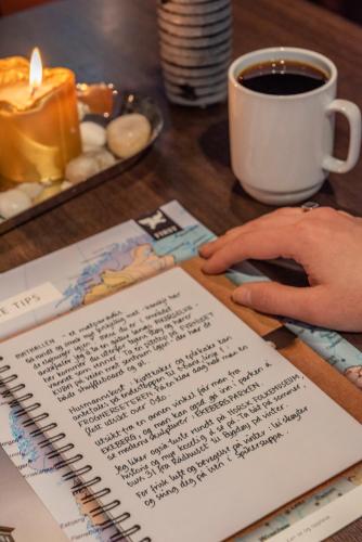 a person sitting at a table with a notebook and a cup of coffee at First Hotel Millennium in Oslo