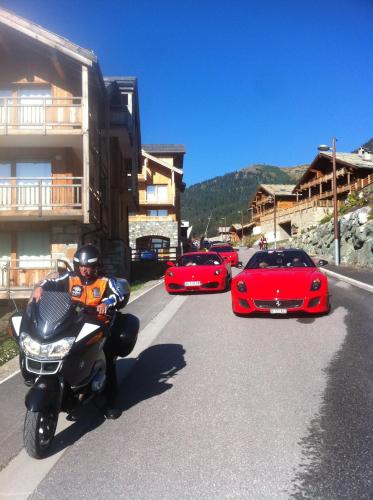 a man riding a motorcycle down a street with cars at Anova Hotel & Spa in Montgenèvre