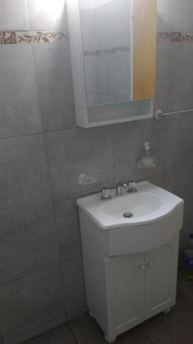 Un baño con un lavabo blanco y un espejo. en El Tatu, en Villa La Bolsa