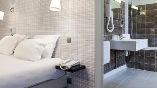 une petite salle de bain avec un lit et un lavabo dans l'établissement La Voile Rouge, à Rosporden