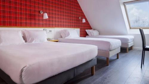 une chambre avec deux lits et un mur rouge dans l'établissement La Voile Rouge, à Rosporden