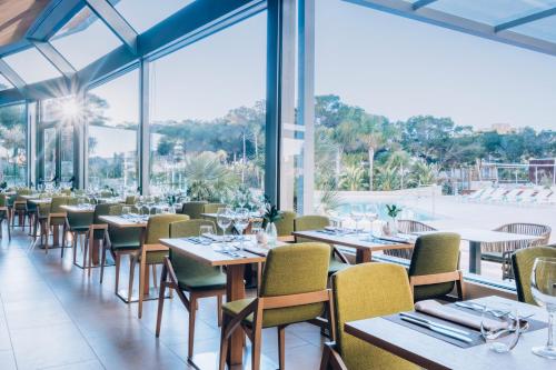 a restaurant with tables and chairs and large windows at Iberostar Selection Llaut Palma- Adults Only in Playa de Palma