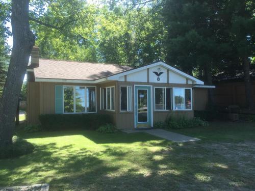 a small house with a tree in a yard at Clear Lake Resort in West Branch
