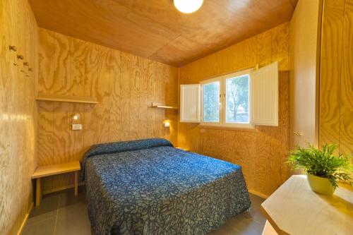 a bedroom with a bed and a potted plant at Camping Lido in Bibione
