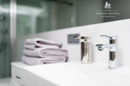 łazienka z 2 umywalkami, lustrem i ręcznikami w obiekcie Grand Hotel Åsgårdstrand - Unike Hoteller w mieście Åsgårdstrand