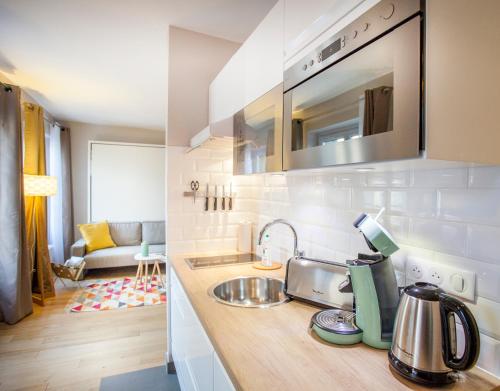 une cuisine avec un évier et un salon dans l'établissement Le Petit Versailles, à Versailles