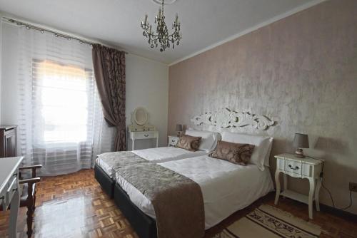 a bedroom with a large white bed and a chandelier at VECCHIA FAVOLA HOUSE in Quarto dʼAltino