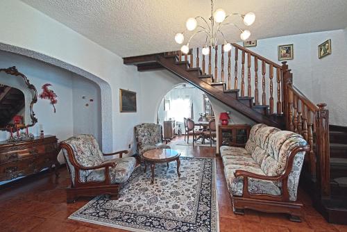 a living room with a couch and chairs and a staircase at VECCHIA FAVOLA HOUSE in Quarto dʼAltino