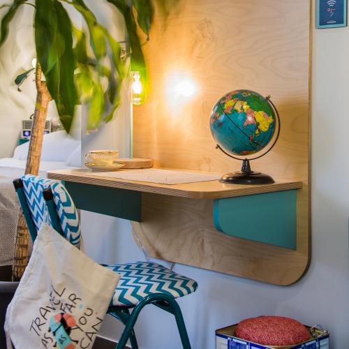 a desk with a globe on a wall next to a chair at The Caravan in Thessaloniki