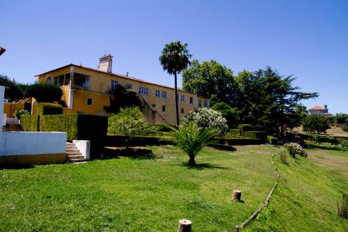 a yard with a building in the background with a tree at Quinta de São José dos Montes in Ferreira do Zêzere