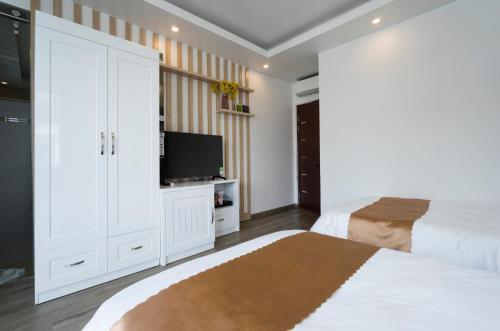a bedroom with two beds and a flat screen tv at BBQ HOSTEL in Ha Long