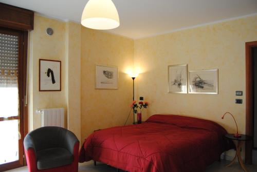 1 dormitorio con 1 cama roja y 1 silla en B&BLeTerrazze BoutiqueHotel2-Torino en Ciriè