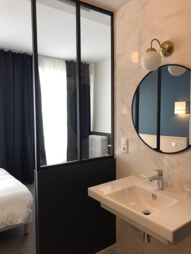 a bathroom with a sink and a mirror and a bed at Hotel Saint Louis in Brest