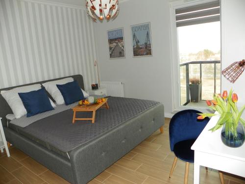 sypialnia z łóżkiem z niebieskimi poduszkami i stołem w obiekcie LIRA Apartament w Gdańsku