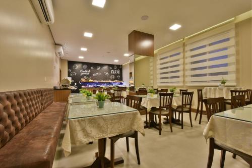 a restaurant with tables and chairs and a chalkboard at Hotel Due Nobili in Gramado