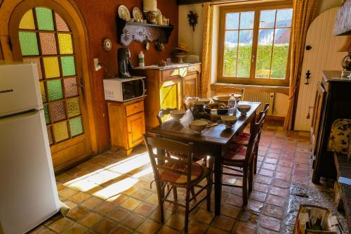 una cucina con tavolo, sedie e frigorifero di LA FRACELINE a Saint-Pierre-dʼEntremont