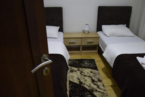 a room with two beds and a door with at Apartmani Marić in Novi Pazar