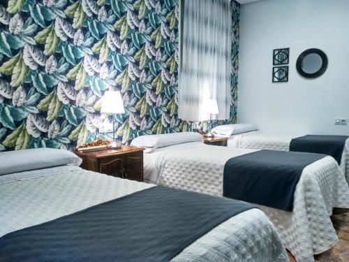 a room with three beds and a wall mural at Hostal Bruña Paseo del Prado in Madrid