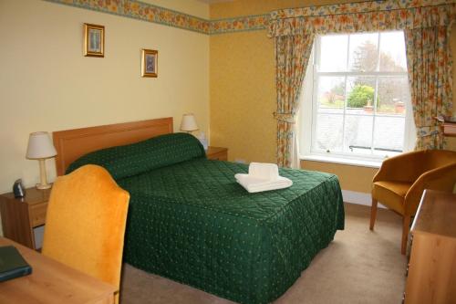 a bedroom with a green bed and a window at Yarn Market Hotel in Dunster