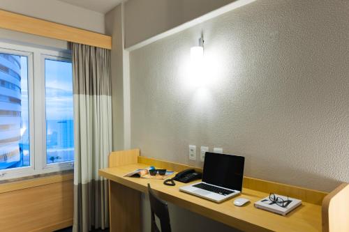 a laptop computer on a desk with a window at ibis Fortaleza Praia de Iracema in Fortaleza