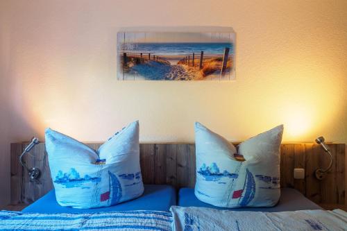 two pillows on a bed with a picture on the wall at Gartenhaus im Ostseebad Trassenheide in Trassenheide