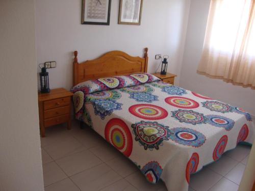 ein Bett mit farbenfroher Bettdecke in einem Schlafzimmer in der Unterkunft Alquileres Cap y Corp in Alcossebre