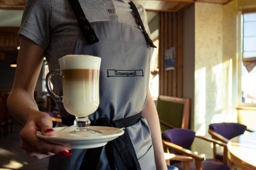 a person holding a cup of coffee on a plate at Готель Поляницький in Bukovel