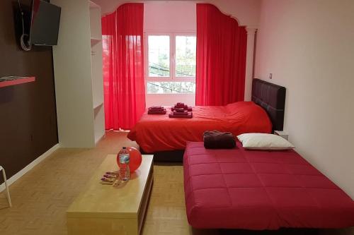 1 dormitorio con cama roja y sofá en Apartamento Adargoma tipo loft en Vecindario