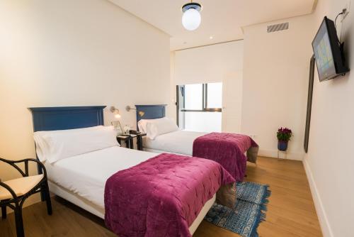 two beds in a hotel room with purple blankets at nüa cicerone in Seville