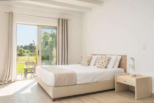 a white bedroom with a large bed and a balcony at ISSOS BEACH VILLA in Línia