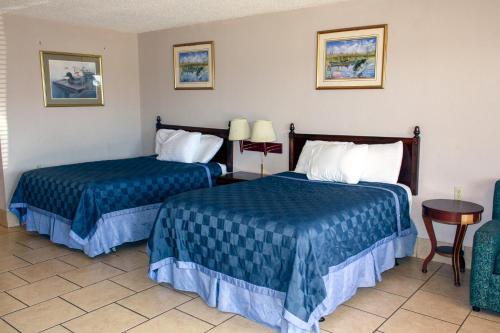 ManyにあるToledo Town Innのベッド2台、テーブルと椅子が備わるホテルルームです。