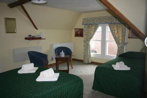 a bedroom with two green beds and a window at Yarn Market Hotel in Dunster