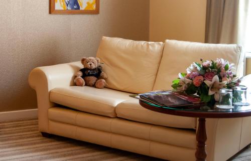 a teddy bear sitting on a couch with a table at Best Western Plus Bentley Hotel in Lincoln