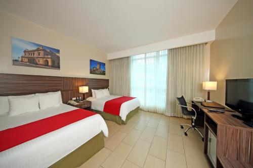 Habitación de hotel con 2 camas y TV de pantalla plana. en Victoria Hotel and Suites Panama en Panamá