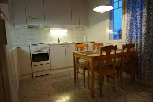 Il comprend une cuisine équipée d'une table, de chaises et d'une cuisinière. dans l'établissement Kappelinrannan Asunnot, à Pargas