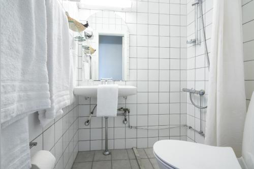a white bathroom with a sink and a mirror at Hotel Dania in Silkeborg