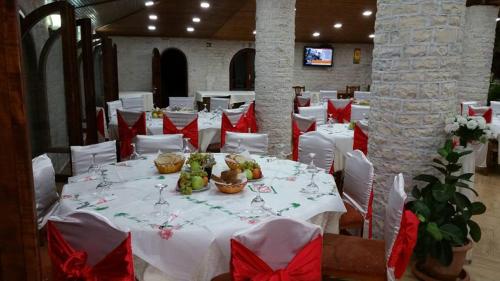 uma sala de jantar com mesas brancas com arcos vermelhos em KT Qato Hotel em Bogovë