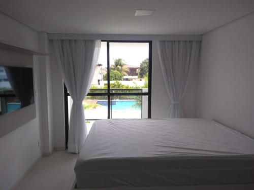 Schlafzimmer mit einem Bett und Poolblick in der Unterkunft Flat Centro de Porto de Galinhas Laguna Beach Flat in Porto De Galinhas
