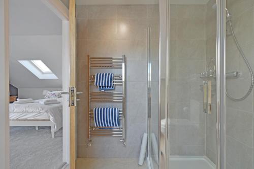 uma casa de banho com um chuveiro, 2 cadeiras e uma cama em Haven Lodge Newquay em Newquay