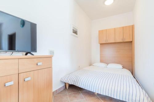 a bedroom with a bed and a flat screen tv at Apartmani Roko in Baška