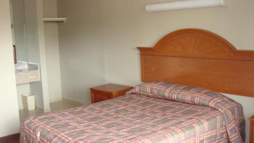 a bedroom with a bed and a wooden headboard at Beauty Rest Motel in Edison