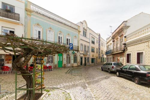 a street with cars parked on a cobblestone street at OlhãOmirante Guesthouse in Olhão