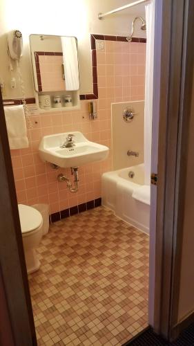 a bathroom with a sink and a tub and a toilet at Holiday Music Motel in Sturgeon Bay