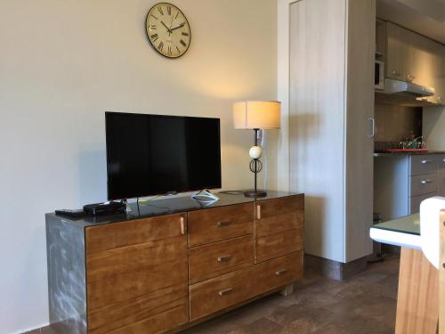 a television on a dresser with a clock on the wall at URBANA SUITES & STUDIOS 440 in San Carlos de Bariloche